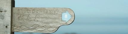A wooden outdoor sign pointing to the South Downs Way walking trail.