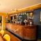 The wood panelled bar and interior restaurant seating area at The Windmill Inn in York, with wine glasses hanging in racks above the counter, and a TV on the wall.
