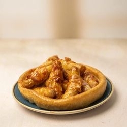 Pigs In Blankets with Peri Peri sauce, served in a giant Yorkshire Pudding on a plate.