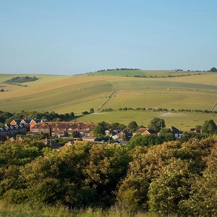 An image of rolling hills and fields with buildings in the distance.