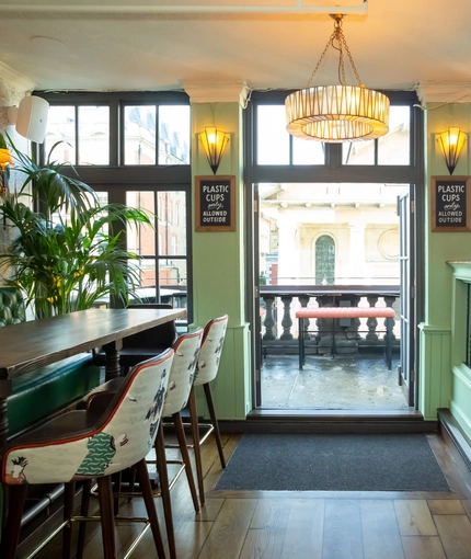Interior of entrance door with high tables on either with bar stools
