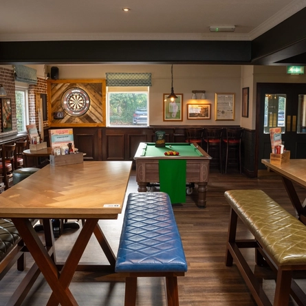 The interior restaurant seating area at The Longship, with upholstered bench seats, a dartboard, and a pool table.