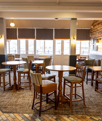Interior dining area of a pub with a bar and a TV.