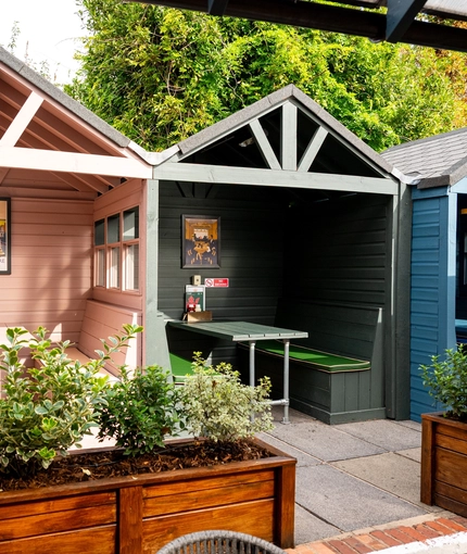 Three sheltered booth seating areas in the beer garden of The Talbot, with padded bench seats.