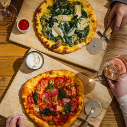 A lifestyle image showing 2 boarded Pizza dishes sat on a table within the interior restaurant seating area at The Four Oaks.