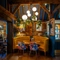 An interior circular booth seating area at The White Hart, with wooden beams, upholstered seats, and potted plants hanging above the table.