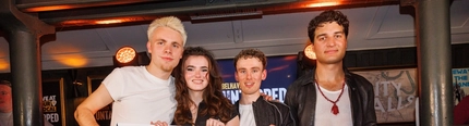 The four members of T-A who are the first ever winners of the Belhaven Untapped competition. The band is standing on a stage at The City Walls in Stirling, holding a giant cheque for £5000.