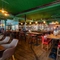 The bar and interior restaurant seating area at the King's Head in Bayswater, with green velvet curtains; green, textured wallpaper on the ceiling; dark wood floor and wall panelling; and a TV hanging above the windows.
