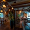 The interior restaurant seating area of The White Hart, with wooden beams, and a TV on the wall.