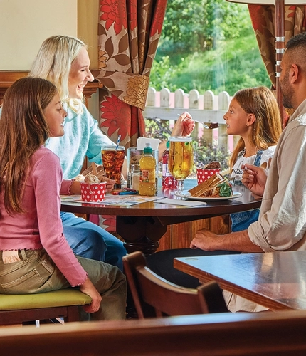 family sitting round a table in a restaurant eating cake and ice cream