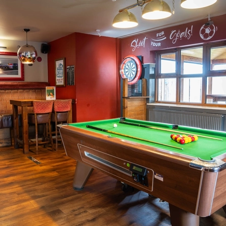 The interior restaurant seating and gaming area, with a dartboard and a pool table.