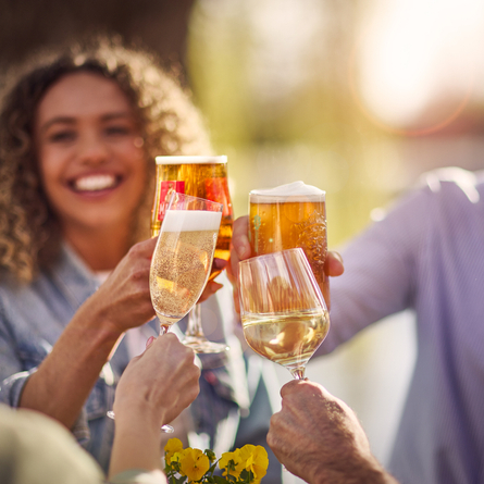 An exterior image showing 4 people sat with a selection of alcoholic drinks celebrating with a cheers at a Chef & Brewer venue.