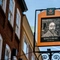 A close up view of the exterior pub sign of the King's Head. The sign features a black and white woodcut-style illustration of a man with a moustache, pointed beard, and shoulder length wavy hair; above the words "King's Head, Bayswater".