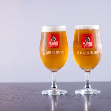 two pints of Madri beer sitting on a wooden table