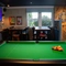 An interior seating and games area at The Horsforth, with a pool table, a TV on the wall, and a dartboard.