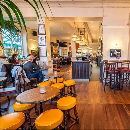 An image of customers sat at tables with drinks within the interior restaurant seating area of The Crabtree.