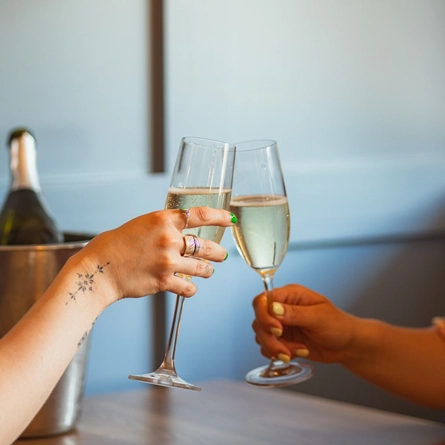 Two women sat at an indoor table, enjoying a glass of sparkling wine.