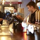 A view looking along the bar at The Flying Horse, featuring customers standing at the bar while members of staff serve them, and a close up view of the beer taps and drinks trays on the bar.