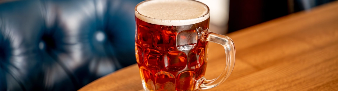 A close up view of a glass of beer on a wooden table inside The Blue Posts.