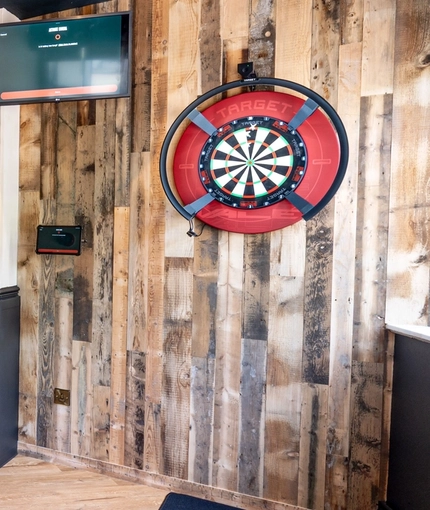 The interior games area at The Bramford Arms in Woodsetton, with a pool table, a dartboard, a gaming machine, a TV on the wall, and restaurant seating.