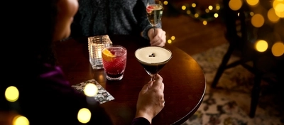 An image of 2 drinks being held and one sat on a table within the interior restaurant and seating area at a Chef & Brewer venue.