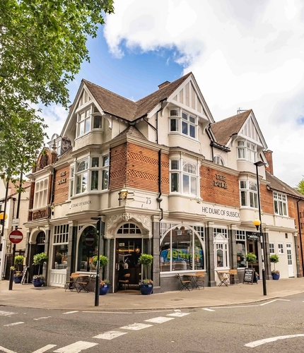The exterior facade with venue signage, potted trees and outdoor seating with tables & chairs at The Duke Of Sussex.
