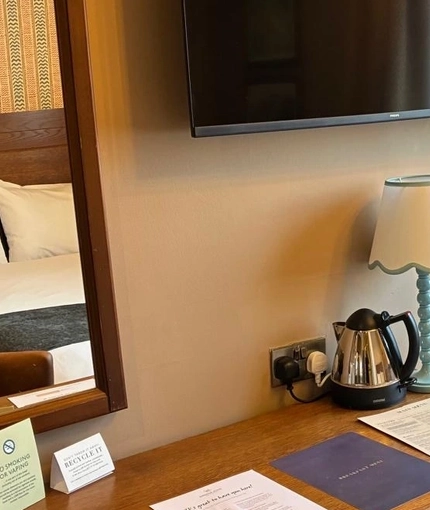 An image showing the interior of one of the hotel rooms featuring bed, dressing table with mirror, hot drinks making facilities and wall mounted TV at The Antelope.
