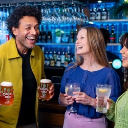 A group of people by the bar enjoying drinks.