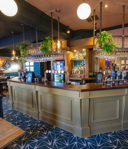 The bar and interior seating area at The Talbot Inn, with a dartboard, and a TV on the wall.