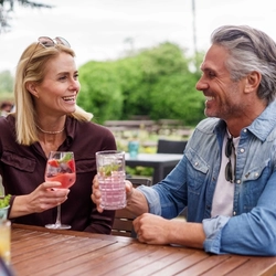 A mixed group of people sat in a beer garden, enjoying cocktails.