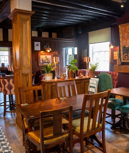 The interior restaurant seating area at The Fox in Bury St Edmunds, with a fireplace and wood panelled walls.