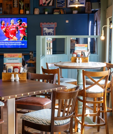 The interior restaurant seating area with a TV on the wall and a pool table, at The Man On The Moon in Ipswich.
