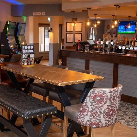 The bar and interior restaurant seating area at The Wall's End, with padded bench seats, TVs on the walls, and gaming machines.