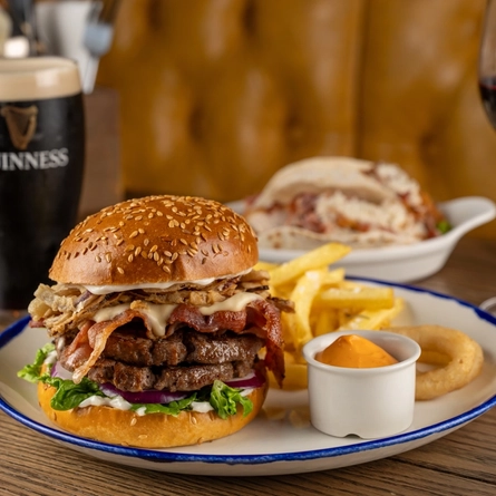 A plated Big Cheese Melt Burger on an indoor wooden table.