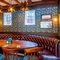 An interior restaurant seating area at The Walkford, with a curved, upholstered booth seat, a large oval wooden table, and framed artwork on the walls.