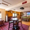 Interior dining area of a pub with a bar, a dartboard, a TV and a pool table.