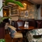 An interior restaurant seating area of The Hollybush, with upholstered chairs, wooden beams, and a fireplace.