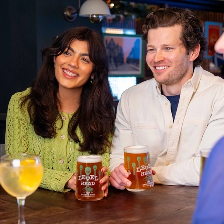 A group of people around a table indoors, enjoying a drink.