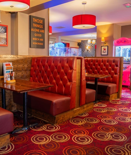 The interior restaurant seating area of The Royal Horse, with wooden tables and upholstered booth seating.