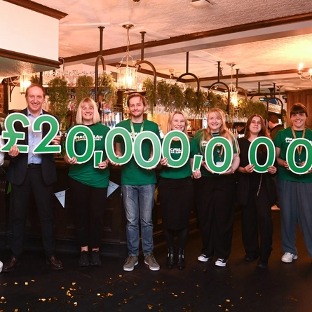 A group of people holding the results of fundraising for Macmillan