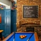 The interior games area at The Windmill Inn, with a pool table, a TV on the wall, and a large brick fireplace.