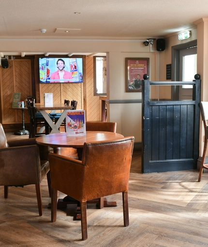 Interior dining area of a pub with a TV and a bar.