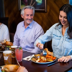 An image of people enjoying a Sunday Roast and various drinks within the interior restaurant seating area at a Community Pubs with Food venue.