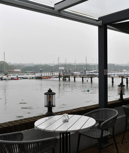 Exterior seating area of a pub next to a body of water.