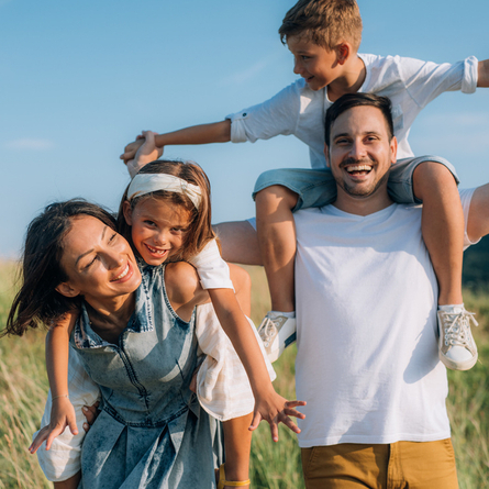 A mother and father with their children on their backs, laughing.