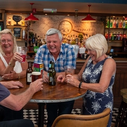a group of people sitting at a table of a Greene King pub drinking beers