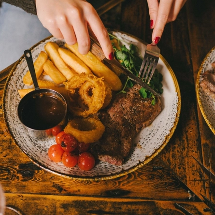 A close up lifestyle image of a Mother's Day Steak and chips main dish sat on a table within the interior restaurant seating area at a Heritage venue.