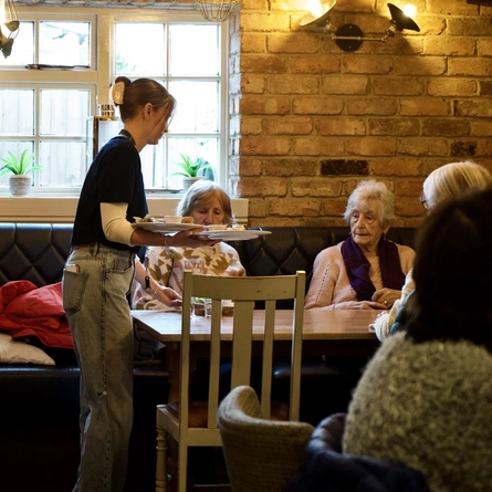 Interior restaurant shot of the Bell. A member of staff serving food to the customers.