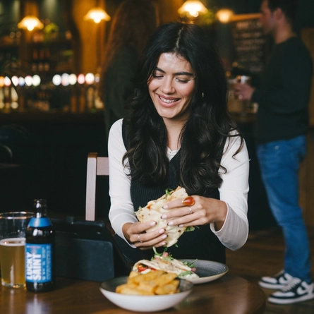 A lifestyle image of a person sat within the interior restaurant seating area enjoying a lunch dish and a drink available at Urban Core venues.