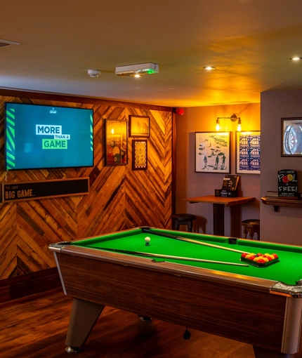 The interior games area at the Counting House, with a pool table, restaurant seating, and TVs on the walls.